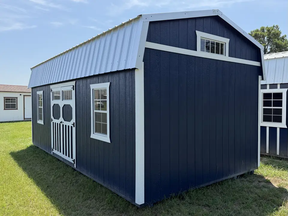 Navy lofted barn with white trim showing double doors with transom windows, two windows and a gable transom window