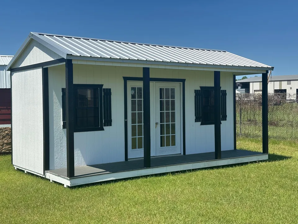White side-porch cabin with black trim, shutters and French doors