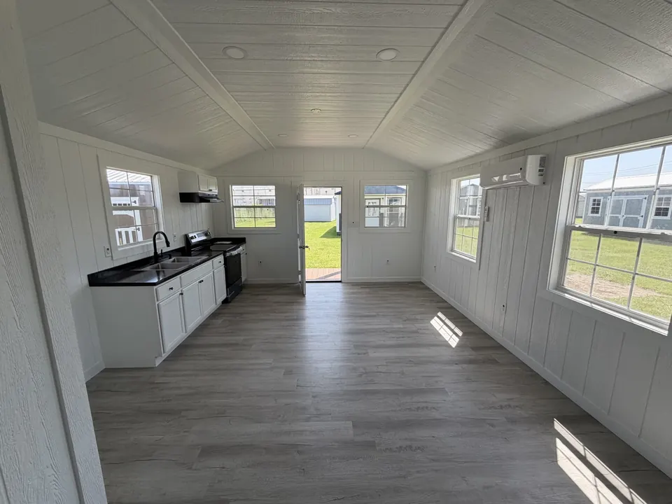 Finished tiny home with a full kitchen along one wall and an open living area