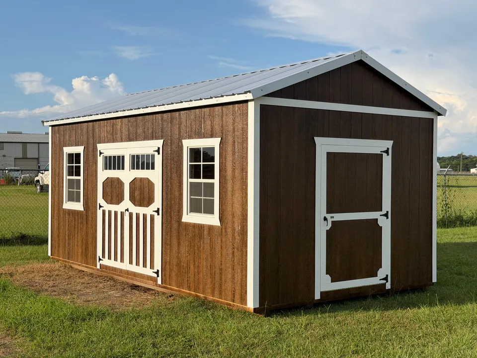 Brown stained utility shed with white trim, double doors with transom windows and a single end door