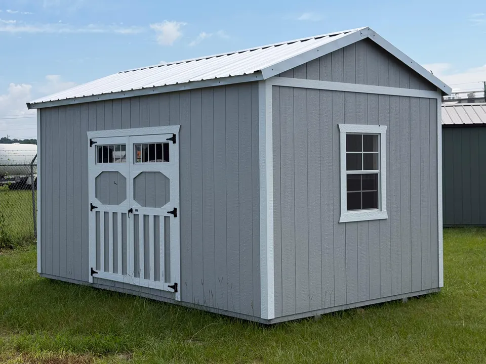 Gray utility shed with white trim and double doors with transom windows