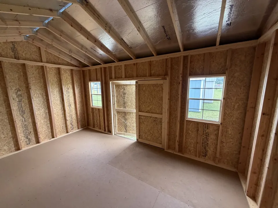 Inside a utility shed with OSB walls, exposed rafters and windows